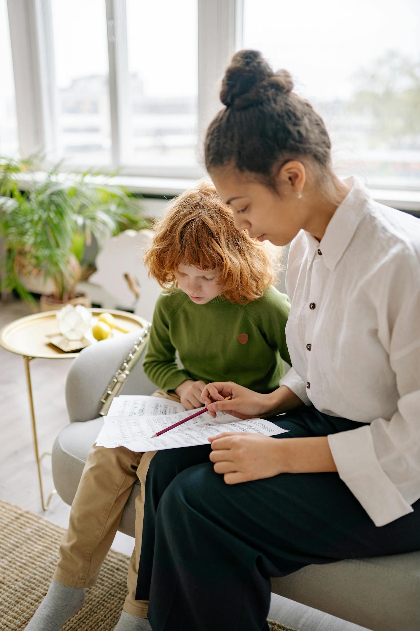 A child receiving educational guidance from an adult indoors, focused and engaging.